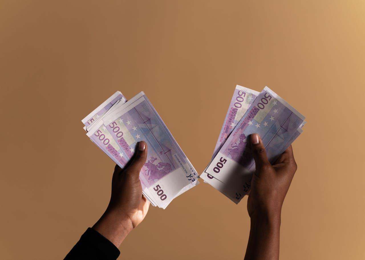 Zwei Hände, geballte Kaufkraft, 500-Euro-Scheine als Symbol für finanzielle Freiheit.