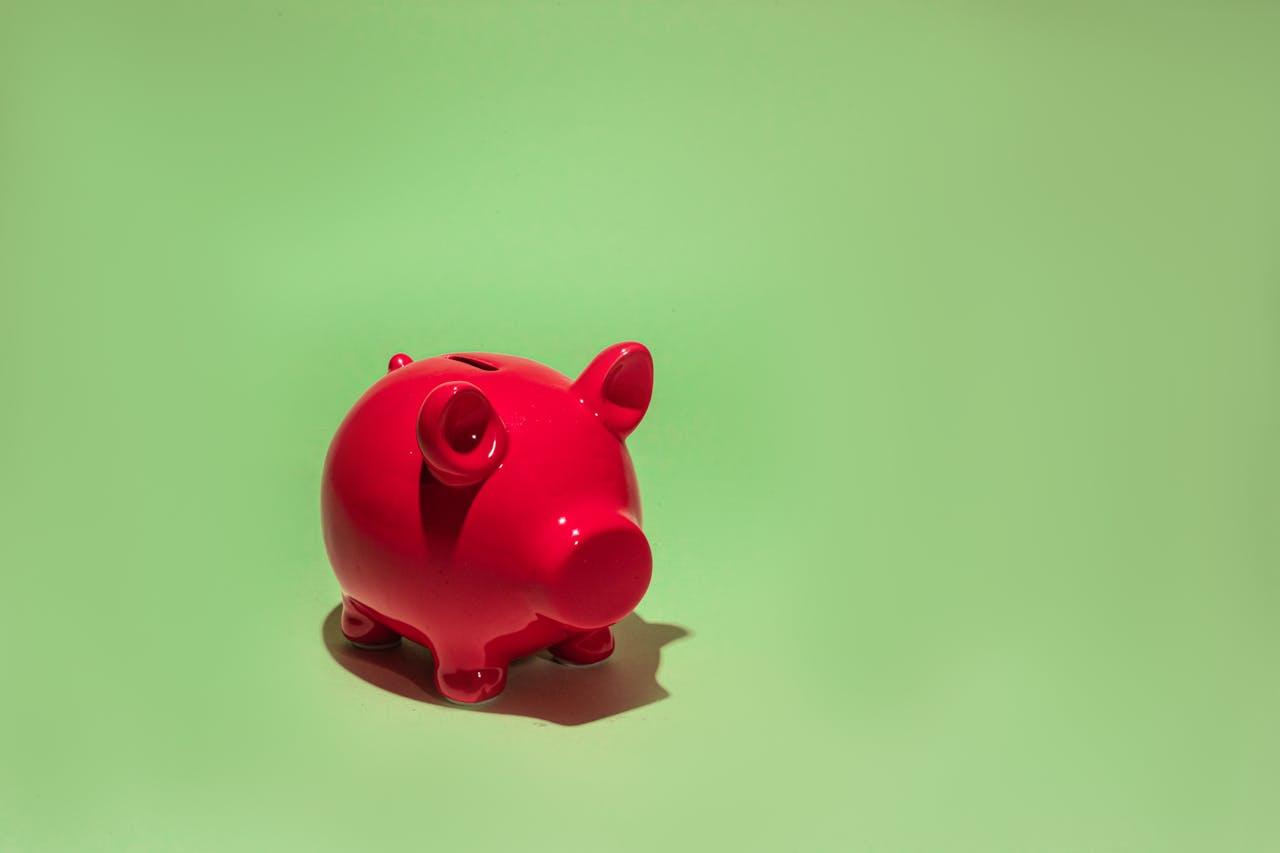 Rotes Sparschwein vor grünem Hintergrund.