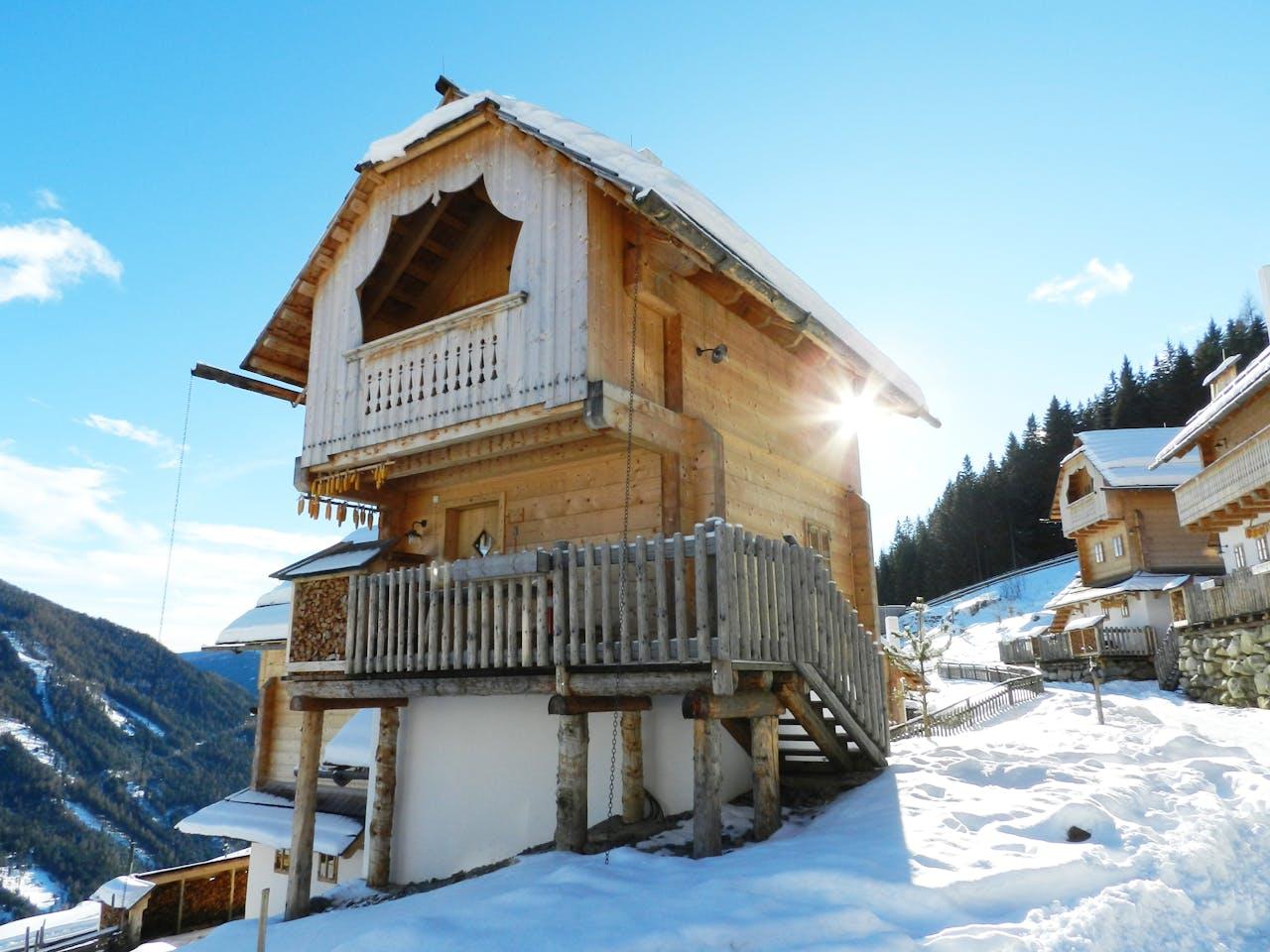Wooden cabin in snow, sunshine.